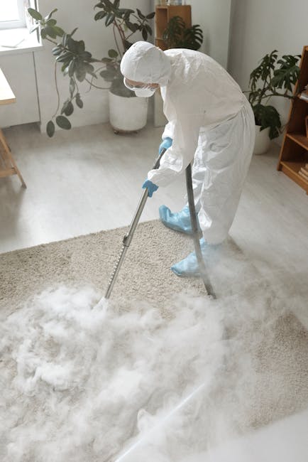 A person wearing a beige shirt and blue jeans is kneeling on a patterned carpeted floor, opening a yellow vacuum cleaner with a black hose. The vacuum cleaner's lid is open, revealing the internal dus
